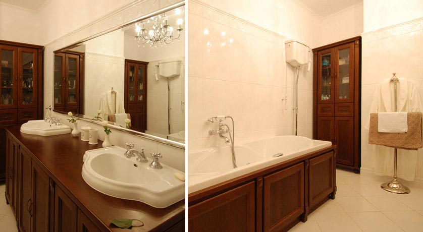 Widok wanny, WC i szafki w stylowej łazience łączącej biel kafli z drewnem zabudowy meblowej