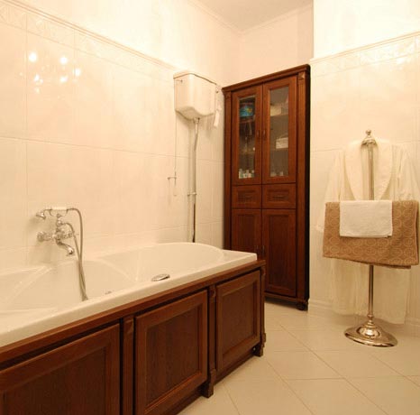 Widok wanny, WC i szafki w stylowej łazience, połączenie bieli i ciemnego drewna