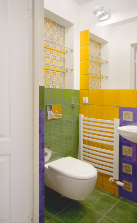 Połączenie bieli ścian i wielokolorowych kafelków w bardzo małej łazience na parterze domu